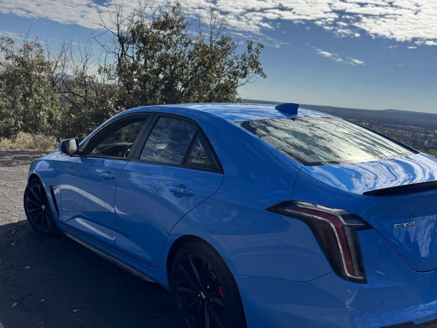 The blue Cadillac parked at an overlook above town